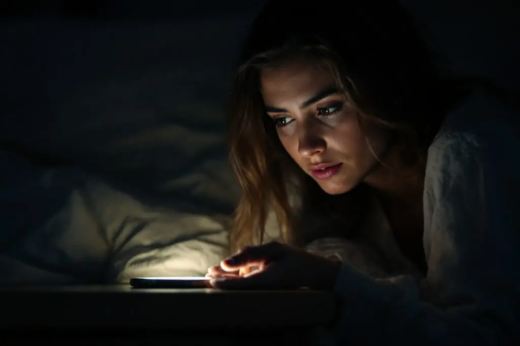 a womans face lit up by a single phone notification in the dark an emotional depiction of breadcrumbing in dating