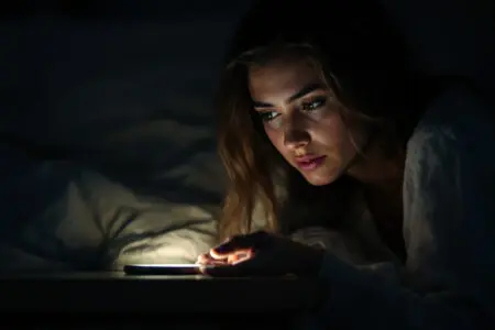 a womans face lit up by a single phone notification in the dark an emotional depiction of breadcrumbing in dating